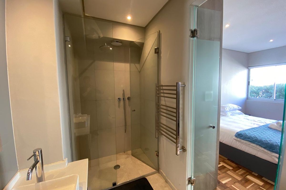 Modern bathroom featuring a glass-enclosed shower, contemporary vessel sink, and a heated towel rail, with direct access to the adjacent bedroom.