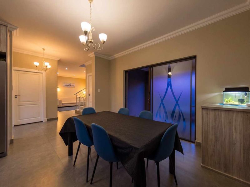 A well-lit dining area featuring tiled flooring, crown molding, and a sliding glass door leading to an adjacent space.