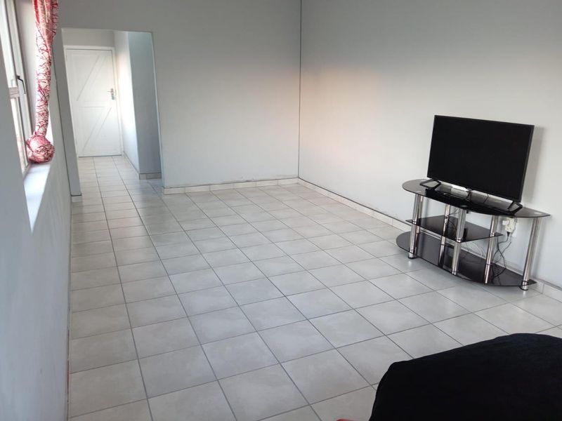 A simple living area featuring neutral tiled flooring and plain walls, providing a blank canvas for interior design updates.