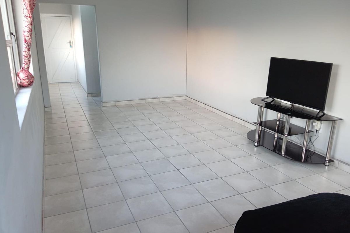 A simple living area featuring neutral tiled flooring and plain walls, providing a blank canvas for interior design updates.