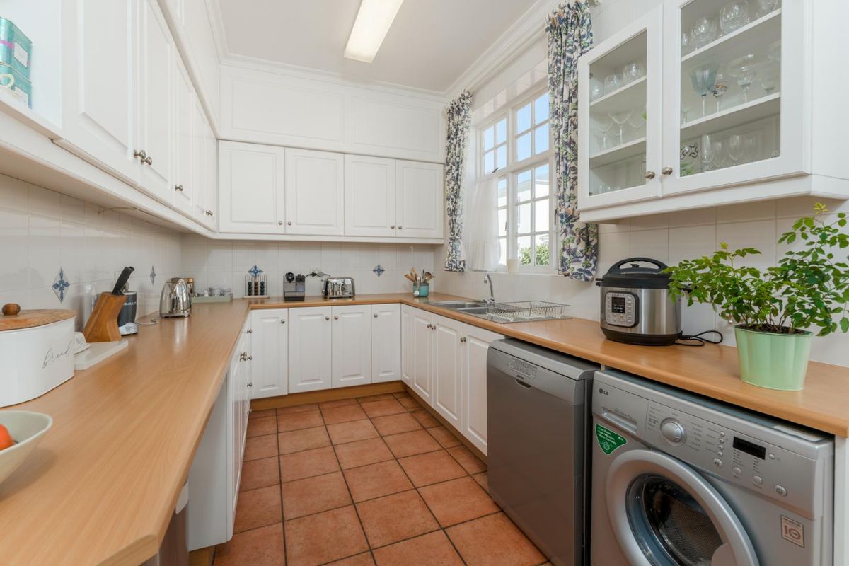 A functional kitchen featuring white cabinetry, wood-look laminate countertops, tiled flooring, and a double basin sink with ample storage space.