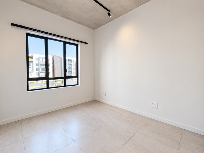 A bright, modern, and empty bedroom featuring tiled flooring, an exposed concrete ceiling, track lighting, and built-in cupboards.