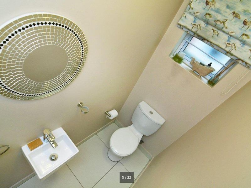 A compact guest bathroom featuring a modern wall-mounted basin, toilet, and neutral tiled flooring.