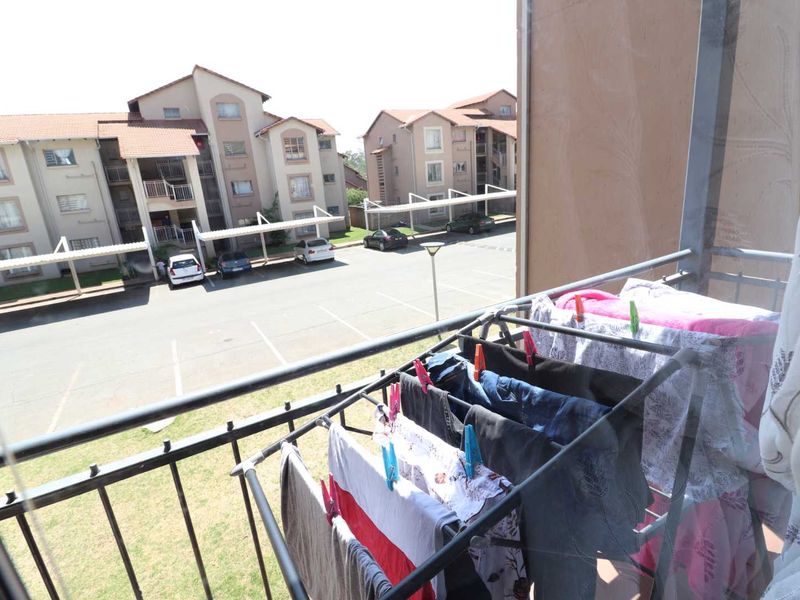 A balcony view overlooking the apartment complex parking area and surrounding residential buildings.