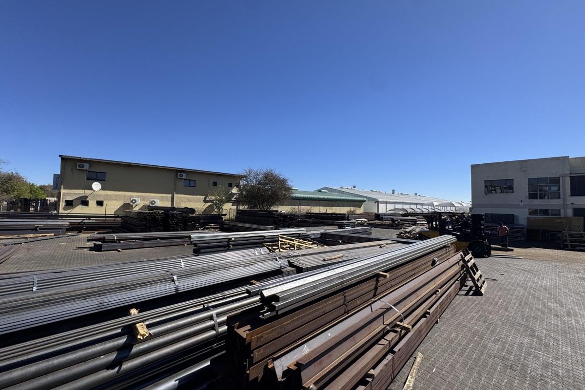 Spacious industrial yard area featuring paved surfaces and multiple warehouse structures, suitable for storage or logistics operations.