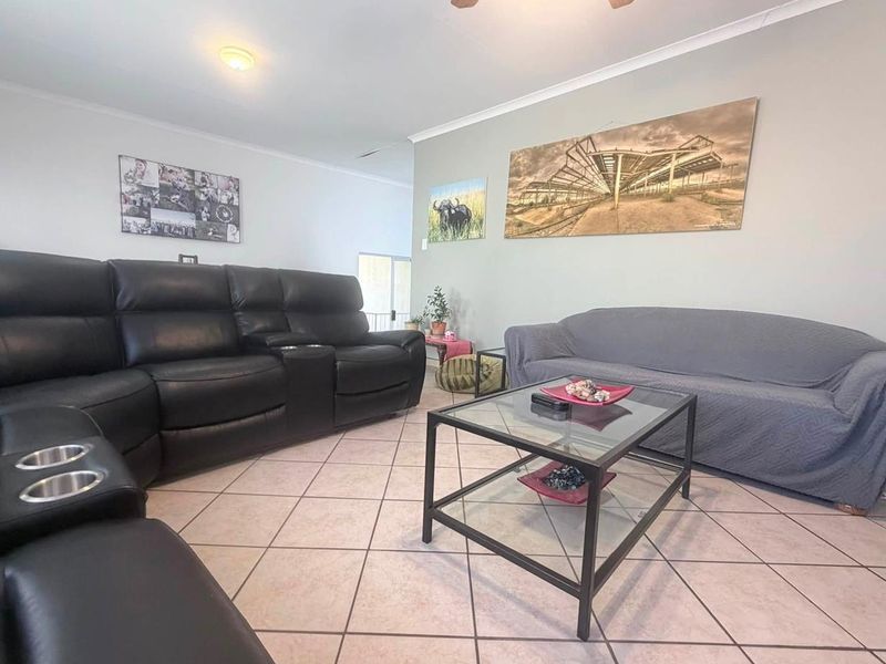 A spacious living room featuring neutral wall tones, ceramic tile flooring, and a ceiling fan, providing a comfortable and functional living area.