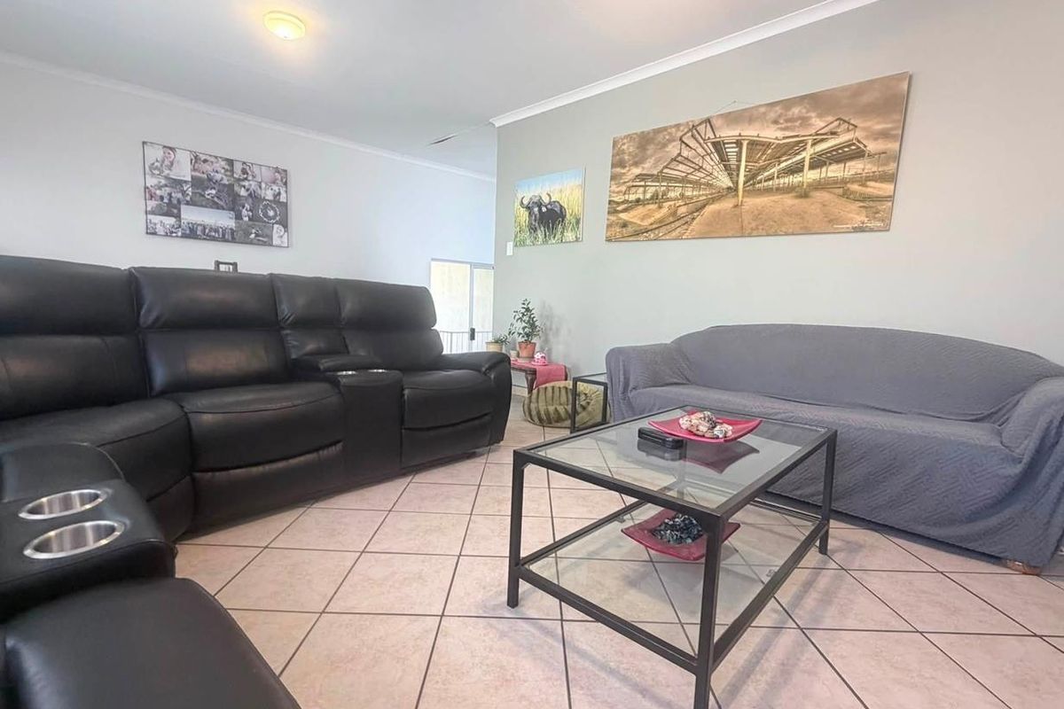 A spacious living room featuring neutral wall tones, ceramic tile flooring, and a ceiling fan, providing a comfortable and functional living area.