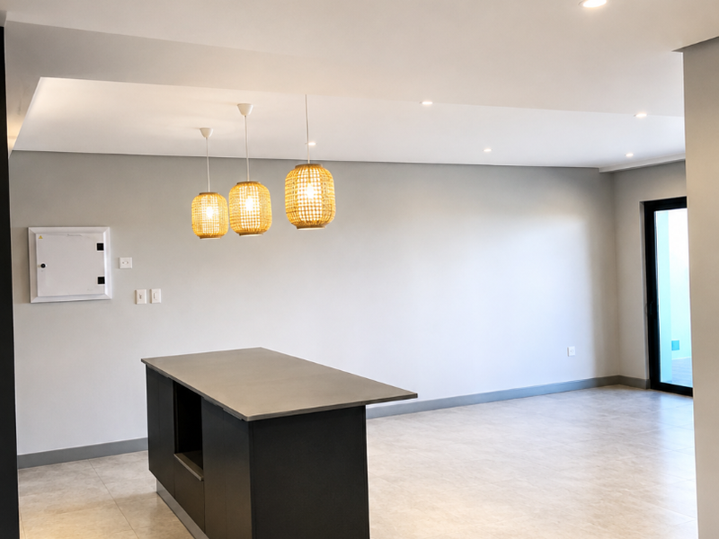 Spacious open-plan living area featuring a modern kitchen island, neutral tiled flooring, recessed lighting, and access to an outdoor area via a sliding door.