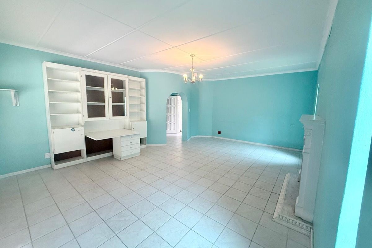 Spacious living room featuring a built-in desk and shelving unit, tiled flooring, and a fireplace mantel, offering a versatile layout for various living arrangements.