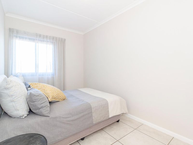 A bright and neutral bedroom featuring tiled flooring and a coved ceiling, offering a clean and simple living space.