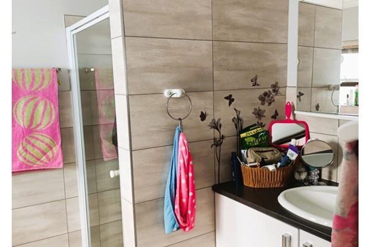 A modern bathroom featuring a glass-enclosed shower, tiled feature wall, and a vanity unit with a built-in sink.