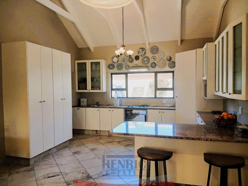 Spacious kitchen featuring white cabinetry, granite countertops, built-in appliances, and a high vaulted ceiling with tiled flooring.