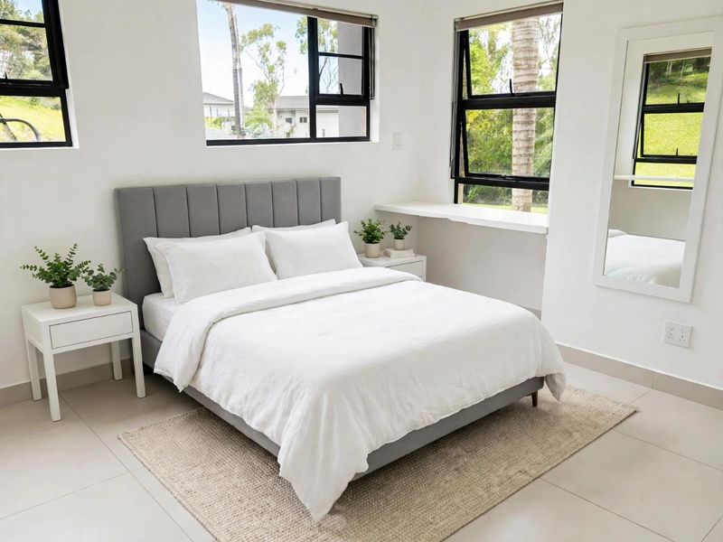 A bright and modern bedroom featuring large casement windows, neutral tiled flooring, and a functional built-in window ledge.