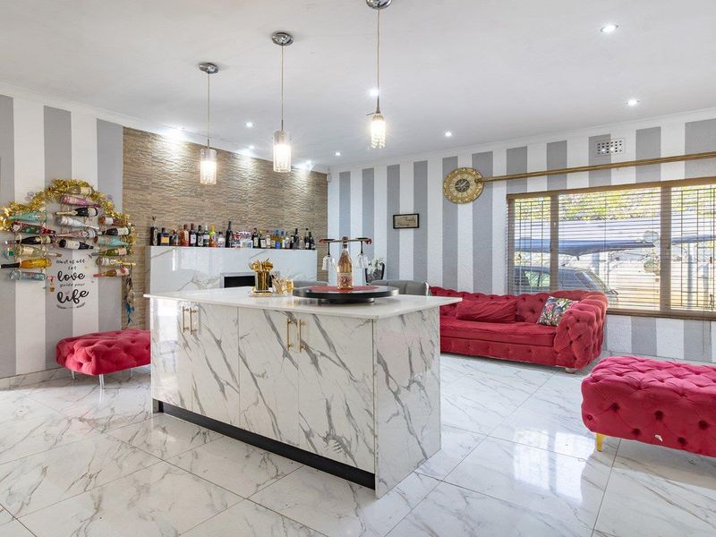 Spacious open-plan living area featuring marble-look floor tiles, a stone-clad feature wall, and a central kitchen island with modern pendant lighting.
