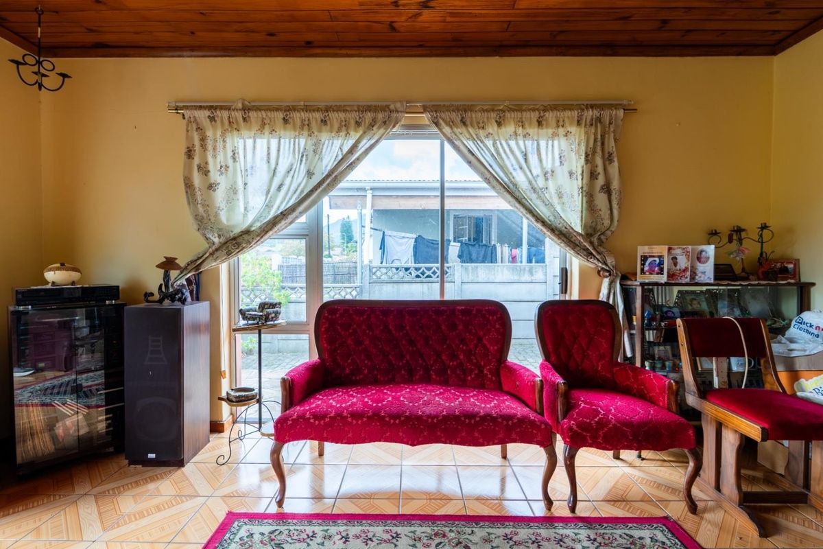 A living room featuring tiled flooring, a timber-paneled ceiling, and a sliding glass door providing access to the rear exterior area.