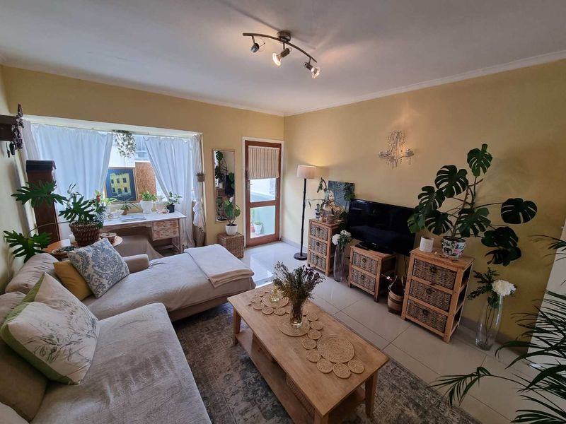 A cozy living room featuring tiled flooring, a multi-directional ceiling light fixture, and a glass panel door leading to an outdoor area.