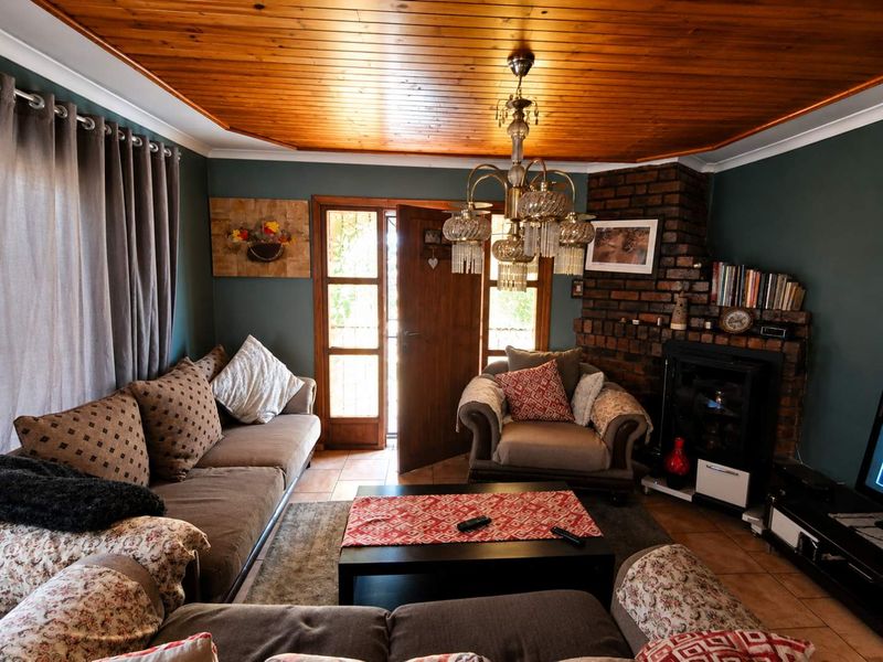 Cozy living room featuring a distinctive timber-clad ceiling, a rustic brick fireplace, and direct access to the outdoors through a glass-paneled timber door.