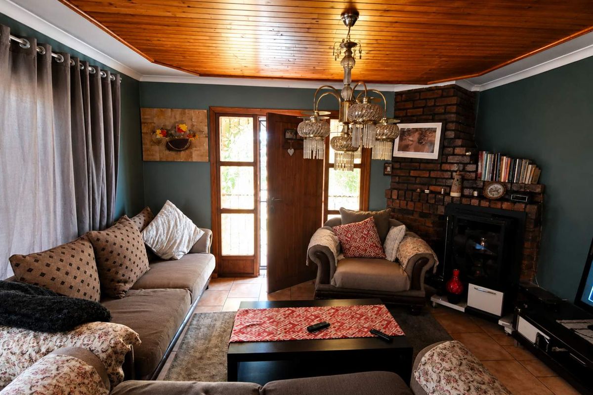 Cozy living room featuring a distinctive timber-clad ceiling, a rustic brick fireplace, and direct access to the outdoors through a glass-paneled timber door.