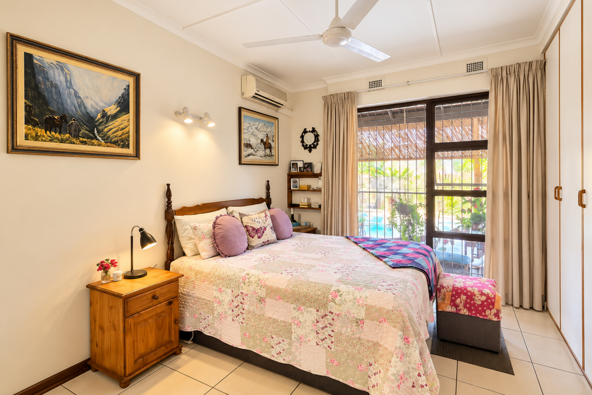A well-maintained bedroom featuring tiled flooring, a ceiling fan, split-system air conditioning, and built-in wardrobes, with direct access to an outdoor area.