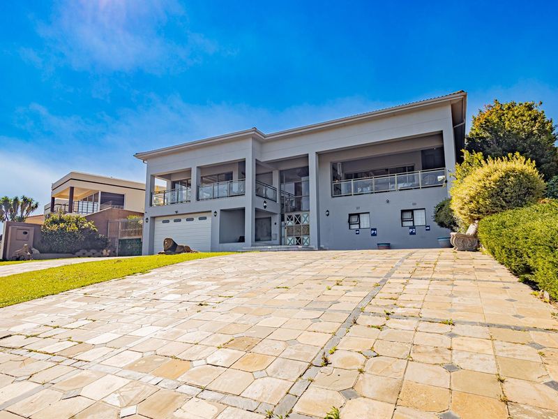 A modern double-story residential property featuring a paved driveway, double garage, and upper-level balconies with glass balustrades.