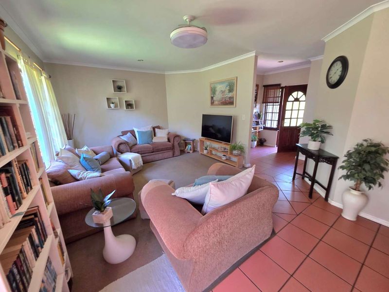 A comfortable living room featuring a mix of tiled and carpeted flooring, coved ceilings, and direct access to the main entrance.