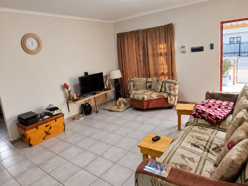 A spacious living room featuring neutral tiled flooring and direct access to an outdoor area, providing a functional and well-lit living space.