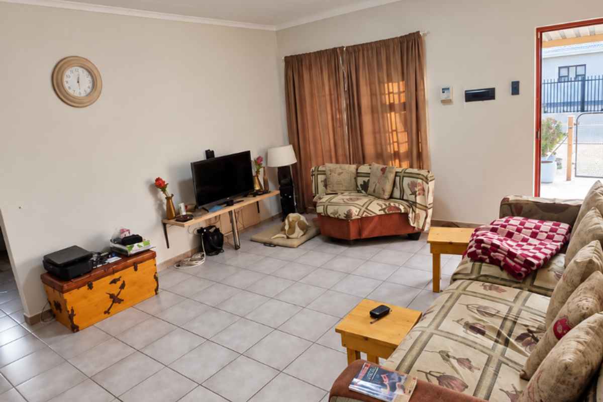 A spacious living room featuring neutral tiled flooring and direct access to an outdoor area, providing a functional and well-lit living space.