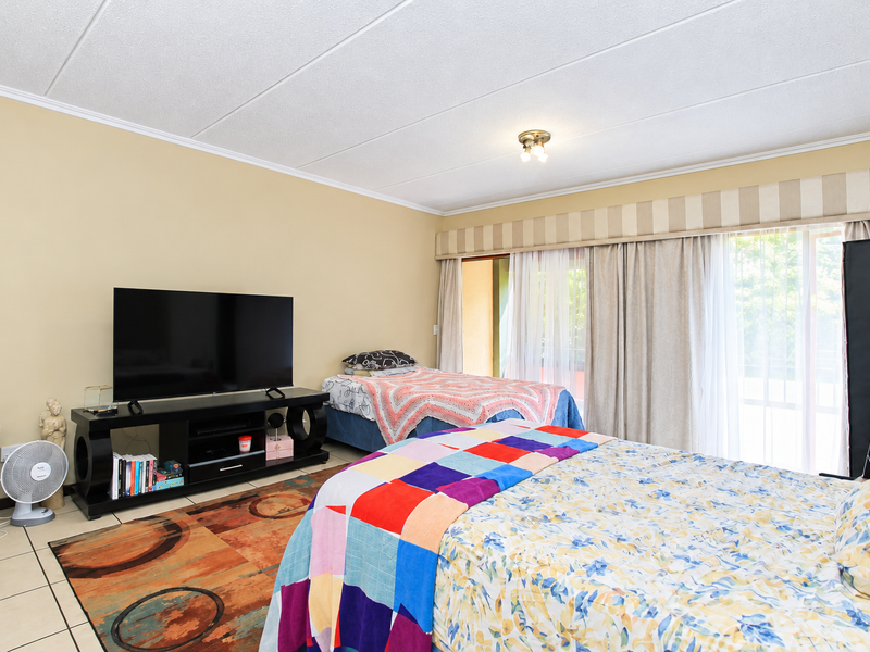 A spacious bedroom featuring tiled flooring and a large sliding glass door that provides access to an outdoor area.