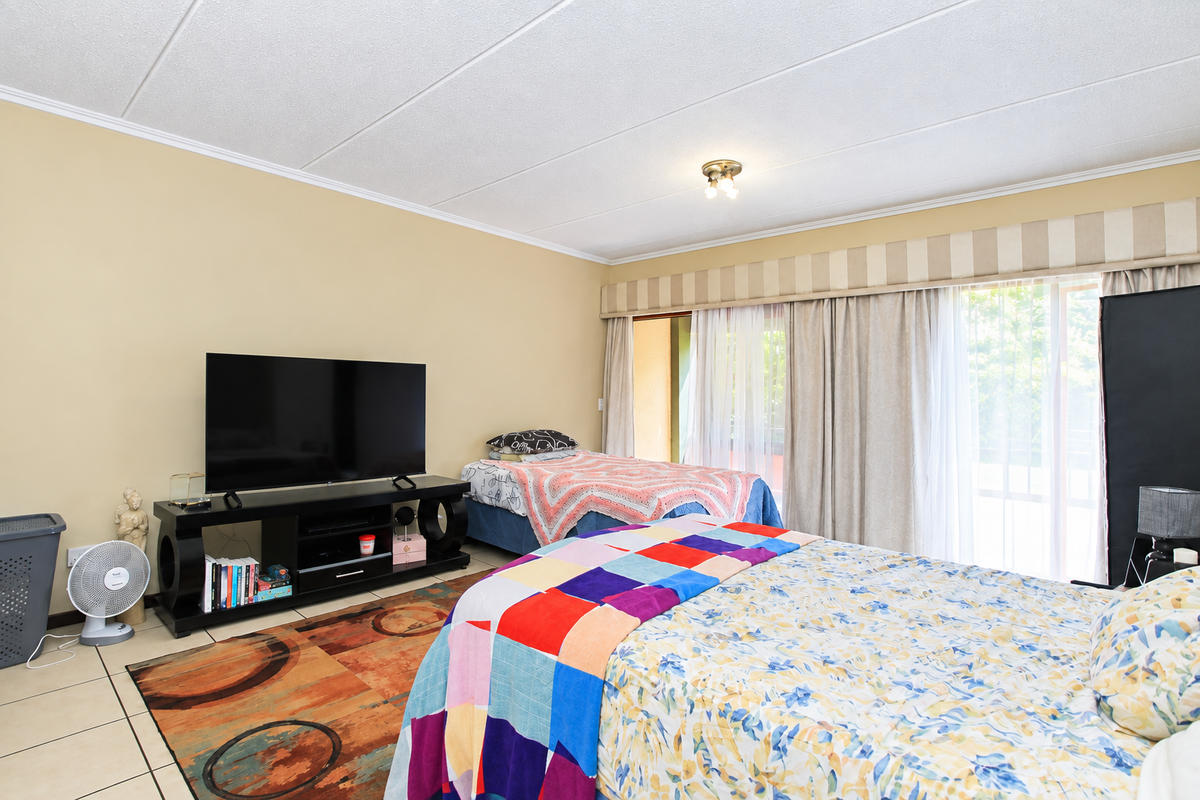 A spacious bedroom featuring tiled flooring and a large sliding glass door that provides access to an outdoor area.