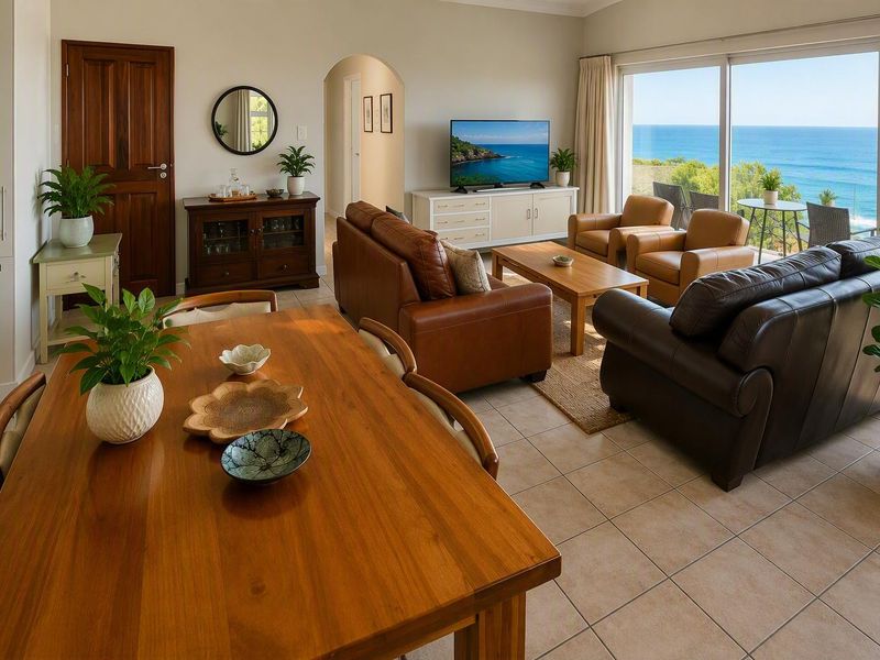 Spacious open-plan living and dining area featuring tiled floors, an arched entryway, and large sliding glass doors offering expansive ocean views.