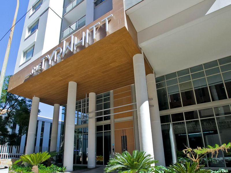 Modern entrance facade of The Tyrwhitt penthouse building, featuring contemporary architectural design, glass curtain walls, and prominent building signage.