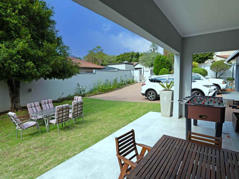 A spacious covered patio overlooking a well-maintained garden and paved driveway area, providing a seamless transition between indoor and outdoor living spaces.