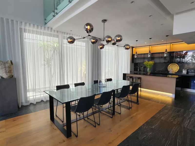 Modern open-plan living area featuring a sleek kitchen with integrated appliances, a central island, and a seamless transition between hardwood and stone flooring.