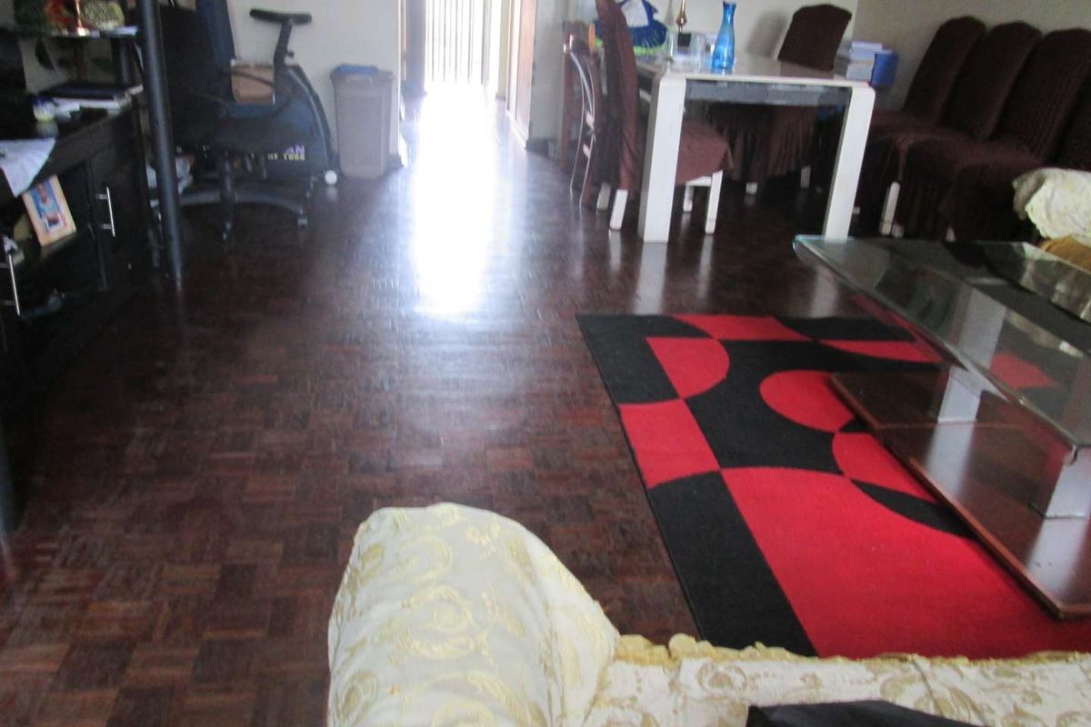 A living and dining area featuring dark parquet wood flooring, leading towards an entrance or hallway.