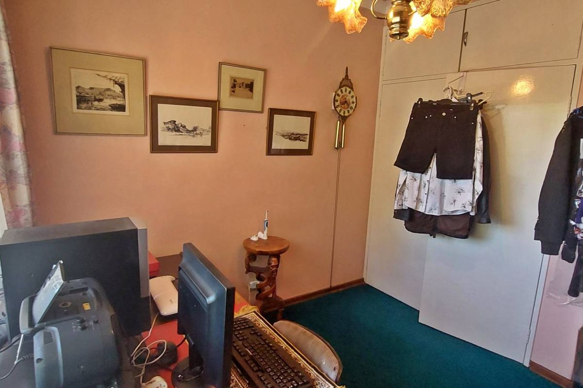 A bedroom featuring built-in cupboards, carpeted flooring, and a window with curtains, offering a functional space for rest or study.