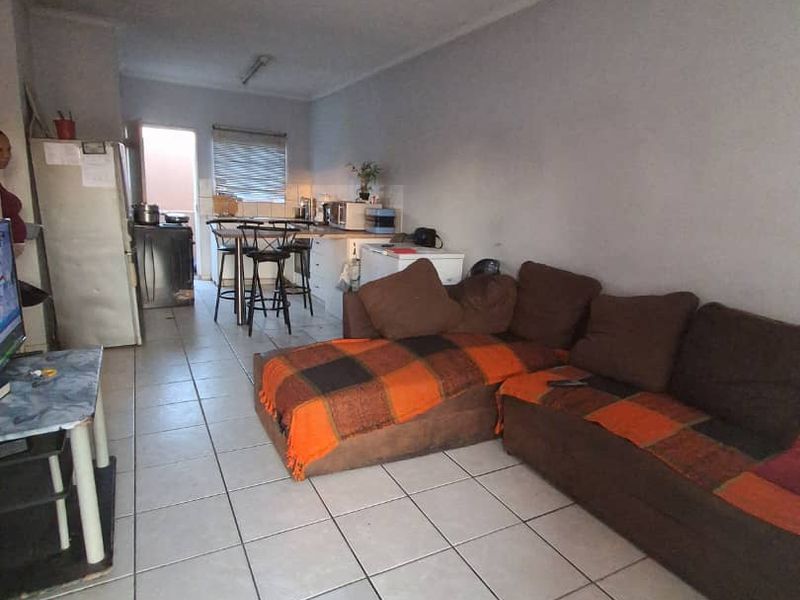 Open-plan living and kitchen area featuring tiled flooring and a functional breakfast bar layout, offering a versatile space for daily living.
