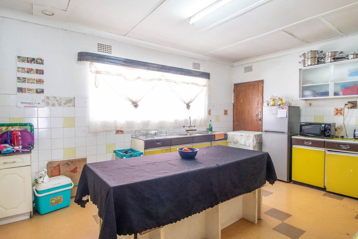 A dated kitchen featuring original cabinetry, tiled splashbacks, and a functional layout with a central workspace, offering significant potential for modernization and renovation.