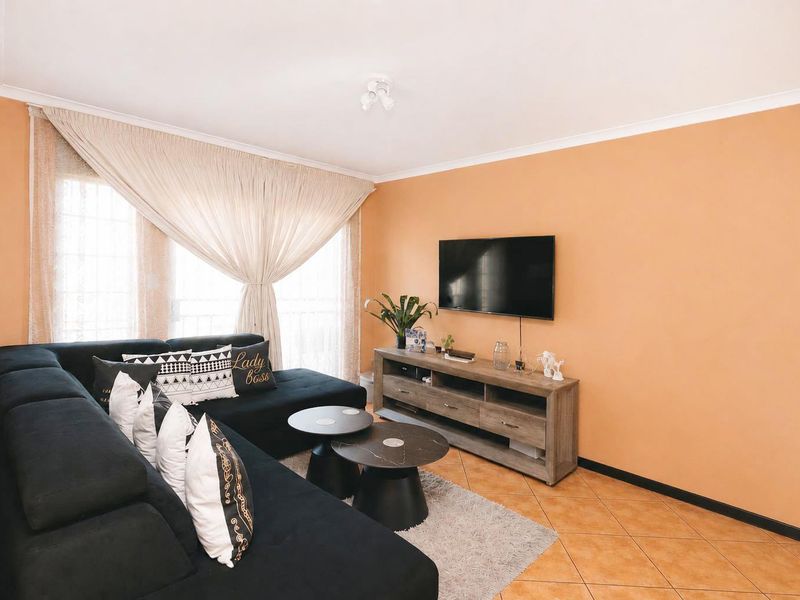A living room featuring ceramic floor tiles, coved ceiling details, and a wall-mounted television setup.