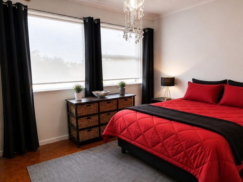 A well-maintained bedroom featuring warm parquet flooring, a built-in wardrobe, and an elegant crystal chandelier, offering a comfortable and inviting living space.