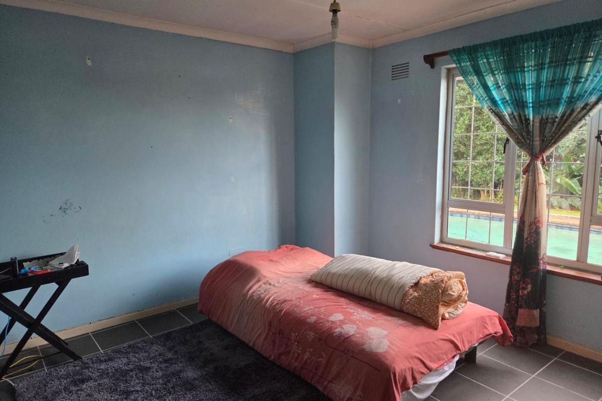 A bedroom featuring tiled flooring and a window with security bars, requiring cosmetic updates to the wall finishes.