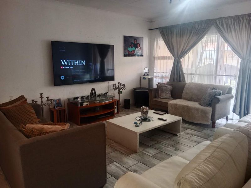 A comfortable living room featuring tiled flooring and large windows with curtain treatments, providing a functional space for relaxation.