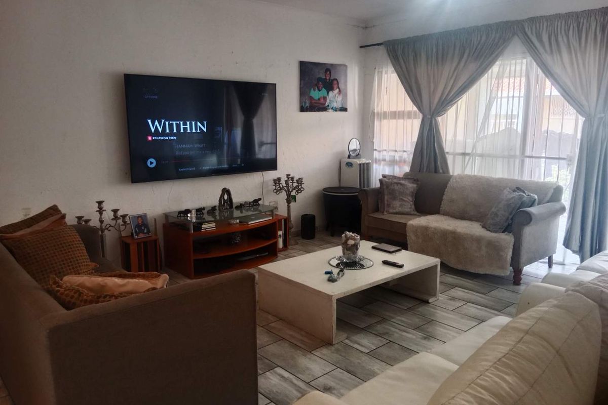 A comfortable living room featuring tiled flooring and large windows with curtain treatments, providing a functional space for relaxation.