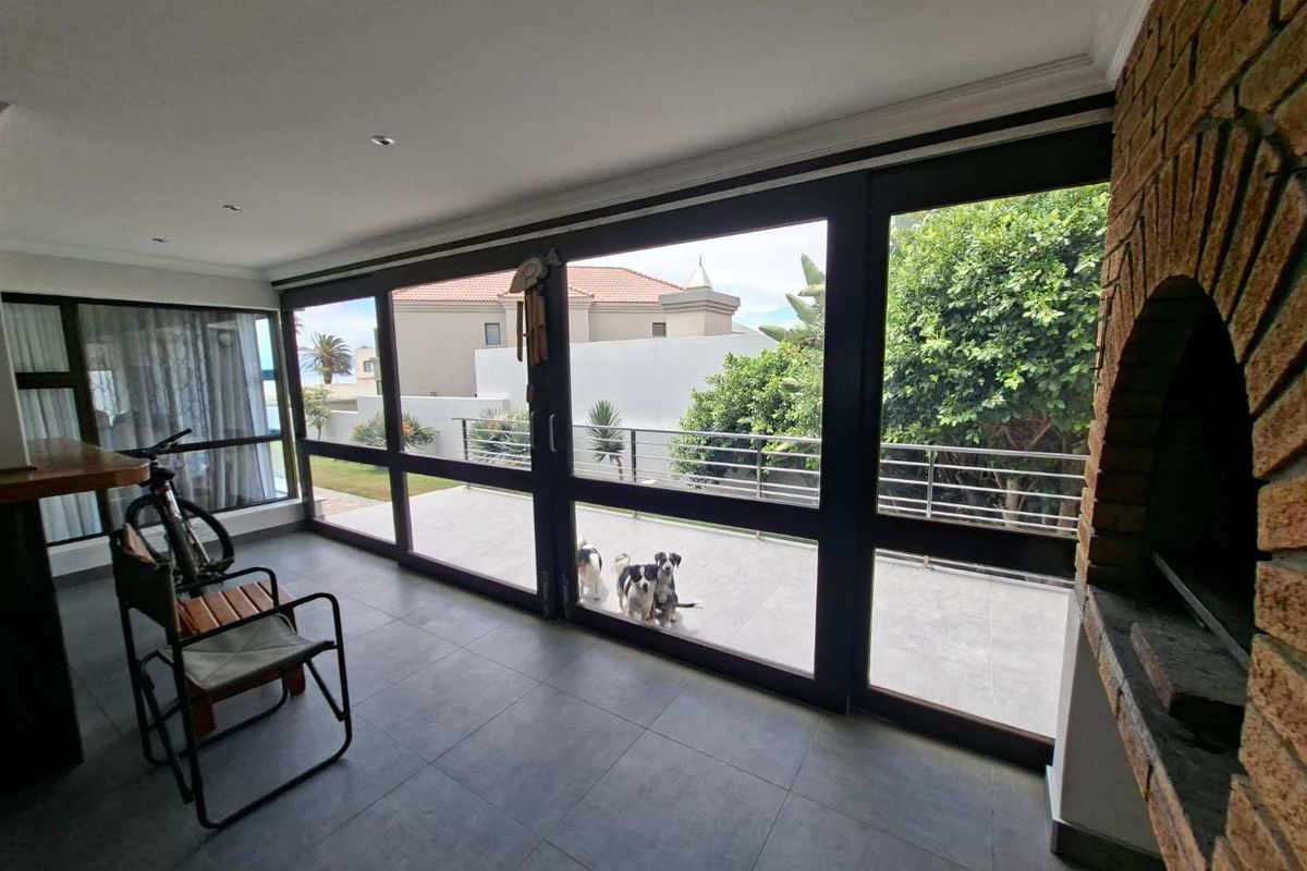 A bright sunroom featuring large glass sliding doors, tiled flooring, and a built-in brick fireplace, offering seamless access to the outdoor patio area.