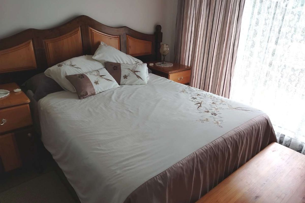 A well-lit bedroom featuring neutral wall finishes and window treatments, providing a comfortable and functional sleeping space.
