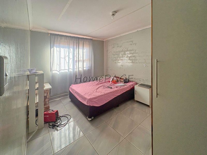 A bedroom featuring tiled flooring and a built-in cupboard, currently requiring cosmetic attention to the wall finishes.