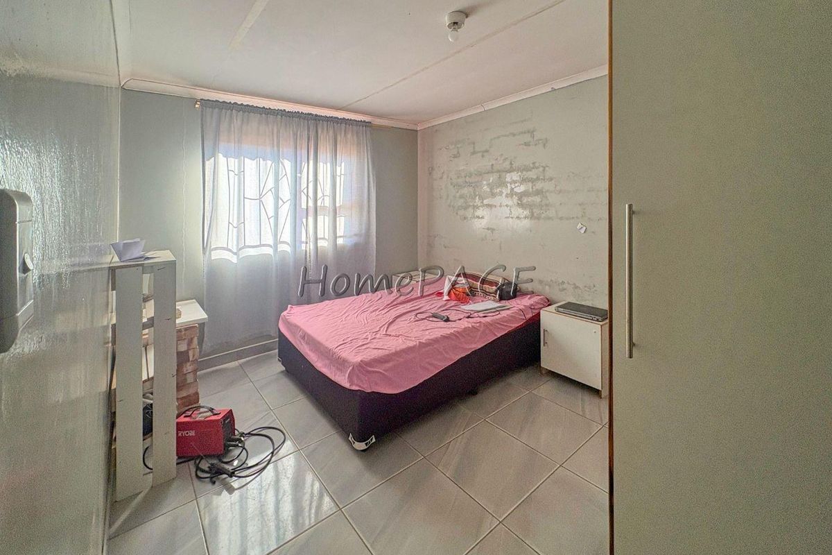A bedroom featuring tiled flooring and a built-in cupboard, currently requiring cosmetic attention to the wall finishes.