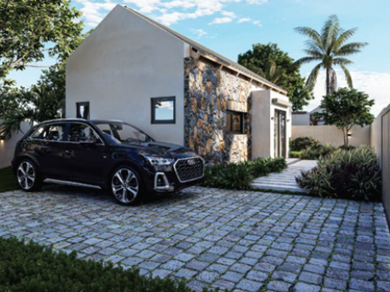 A modern residential facade featuring stone cladding, a neat cobblestone driveway, and landscaped garden areas.