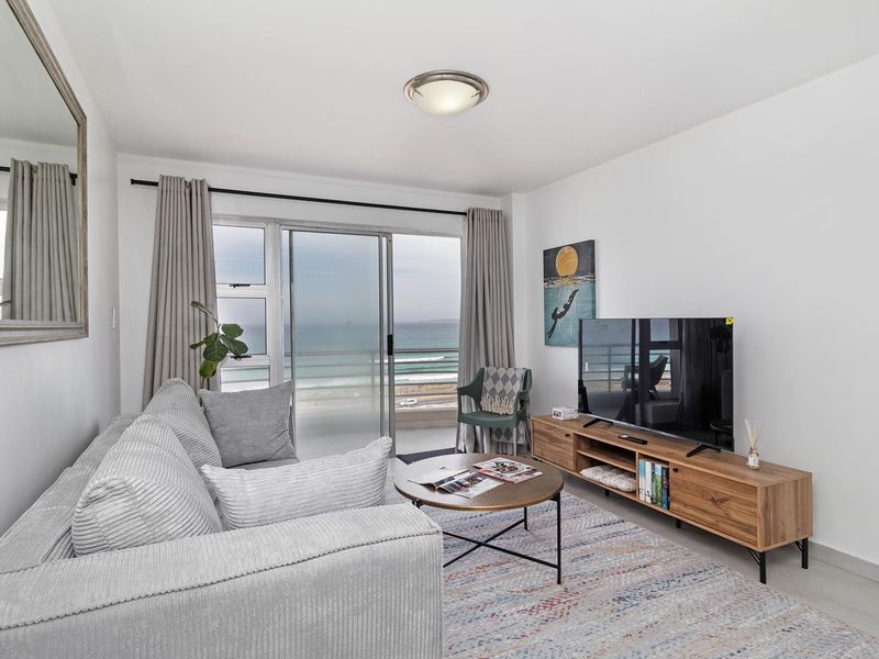 A bright living room featuring a sliding glass door with direct access to a balcony and scenic ocean views.