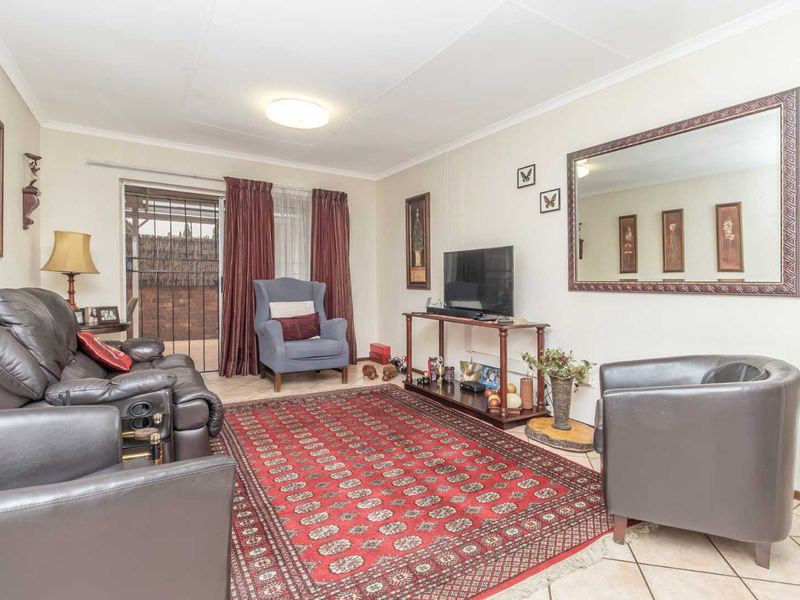 A comfortable living room featuring tiled flooring and a sliding glass door with security gate, providing access to the outdoor area.