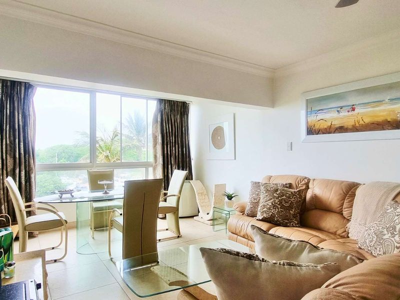 Open plan living and dining area featuring large windows with natural light and neutral tiled flooring.